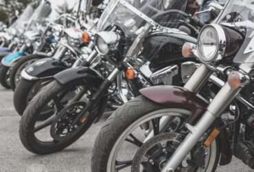 A close-up of several motorcycles parked in a neat row. Each bike is a different color and has a different front-end style.