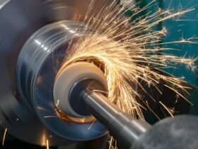 A piece of metal machinery is shooting off orange sparks in a radial pattern. There is a shaft inserted into the metal machine.