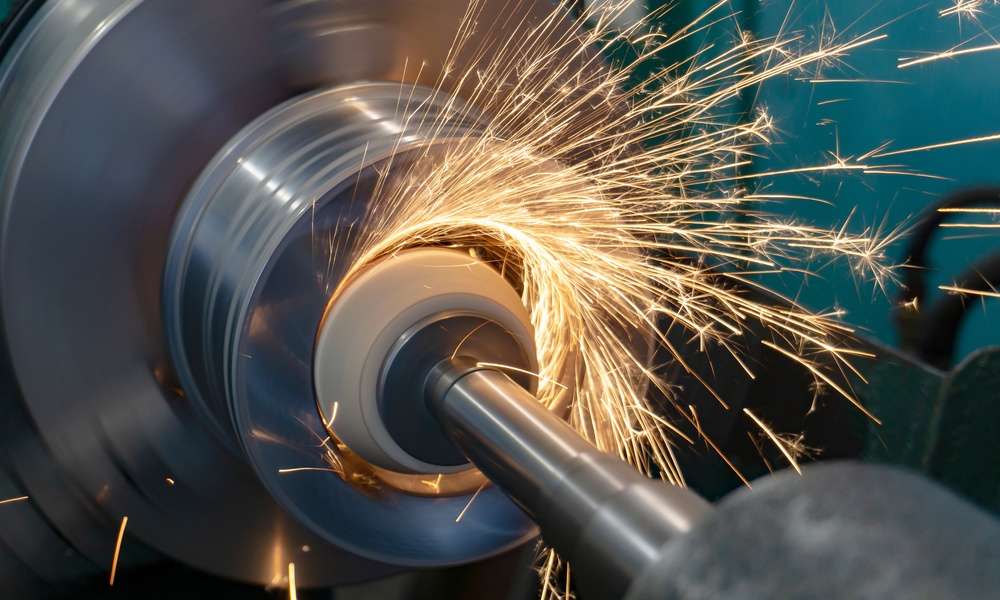 A piece of metal machinery is shooting off orange sparks in a radial pattern. There is a shaft inserted into the metal machine.