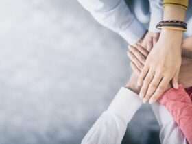 An aerial view shows several people placing their hands in the center of a circle, stacking them on top of each other.