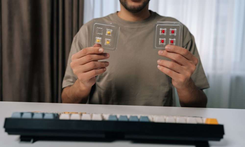 A man holds several mechanical keyboard switches while comparing parts for a custom mechanical keyboard project.