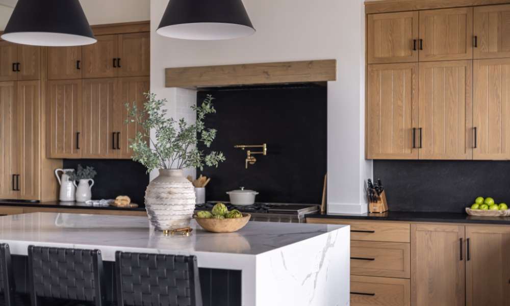 A modern kitchen with rustic wooden cabinets and a black backsplash. There is also an island with a flower vase on it.