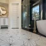 Black and white bathroom with hexagon floor tile, glass shower, vanity, and mirror viewed from a low angle.