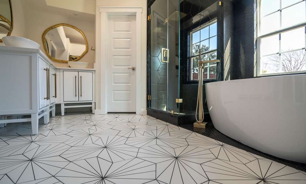 Black and white bathroom with hexagon floor tile, glass shower, vanity, and mirror viewed from a low angle.
