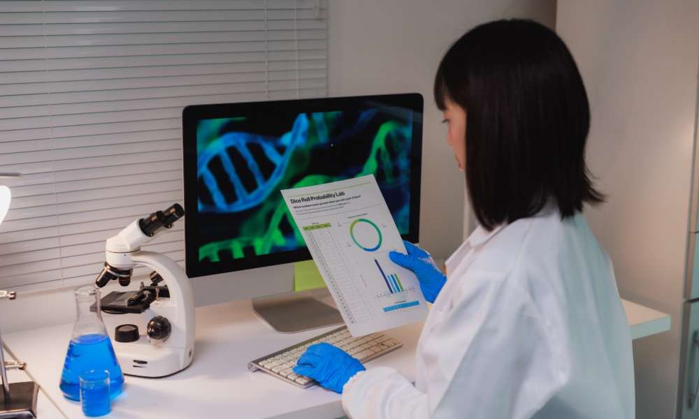 A female lab scientist at the work desk in front of a monitor, reading the results to the lab test she ran.
