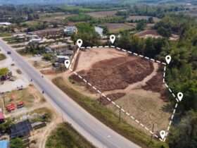 An aerial view of an open plot of land in a neighborhood. The plot is outlined by a dotted white line.