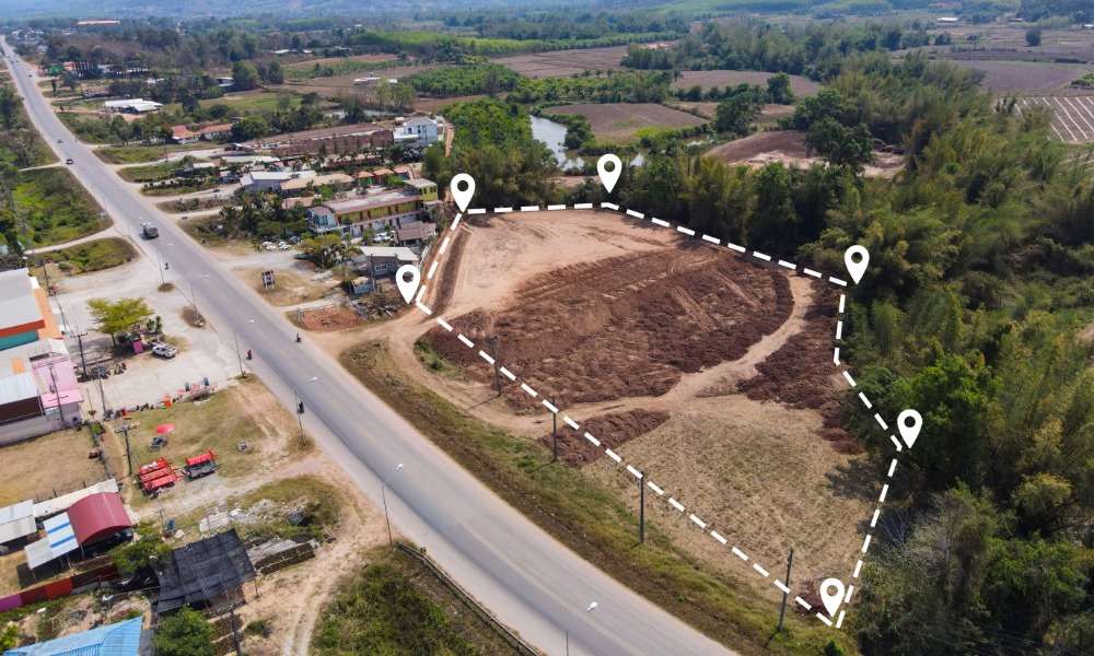 An aerial view of an open plot of land in a neighborhood. The plot is outlined by a dotted white line.