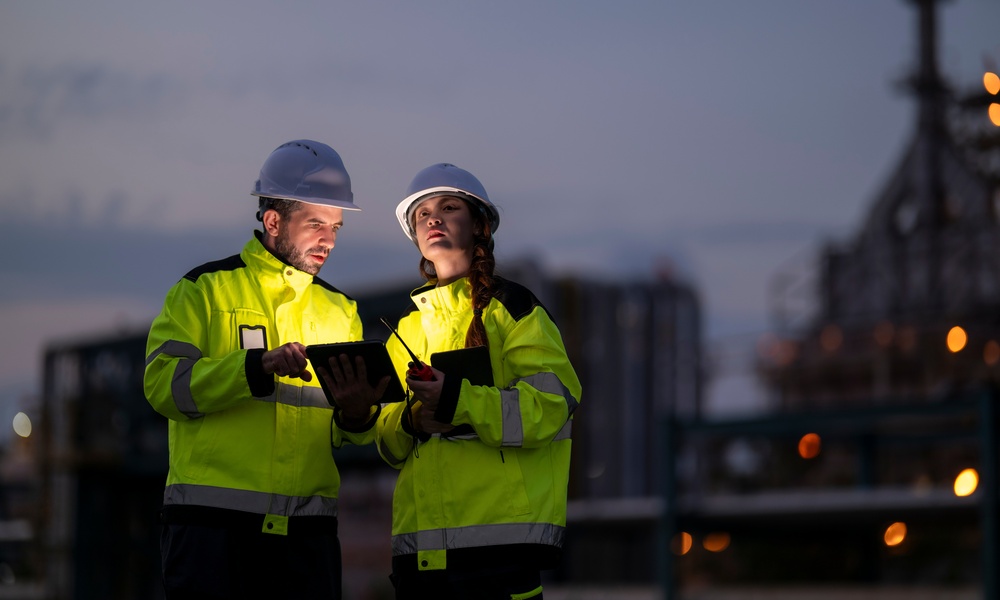 Two people are standing next to each other, one man and one woman. They are both wearing hi-vis jackets.