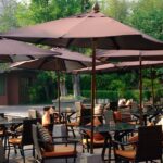 Multiple tables and chairs with orange cushions in an outdoor space under brown umbrellas with metal bases.Multiple tables and chairs with orange cushions in an outdoor space under brown umbrellas with metal bases.