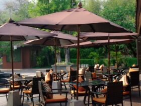 Multiple tables and chairs with orange cushions in an outdoor space under brown umbrellas with metal bases.Multiple tables and chairs with orange cushions in an outdoor space under brown umbrellas with metal bases.