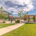 A children's playground sits next to a covered picnic area. A concrete path leads to the seating area and playground.