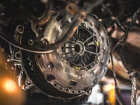 Exposed clutch assembly sits inside a vehicle undercarriage. Wires and hoses hang around the metal housing.