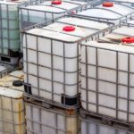 Intermediate bulk containers for chemicals stacked on top of one another. Some IBCs appear discolored.