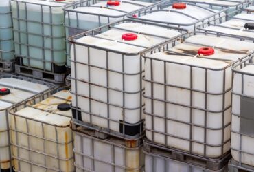 Intermediate bulk containers for chemicals stacked on top of one another. Some IBCs appear discolored.
