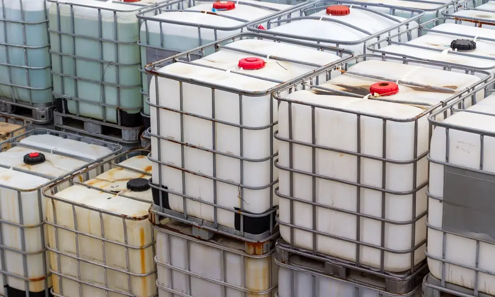 Intermediate bulk containers for chemicals stacked on top of one another. Some IBCs appear discolored.