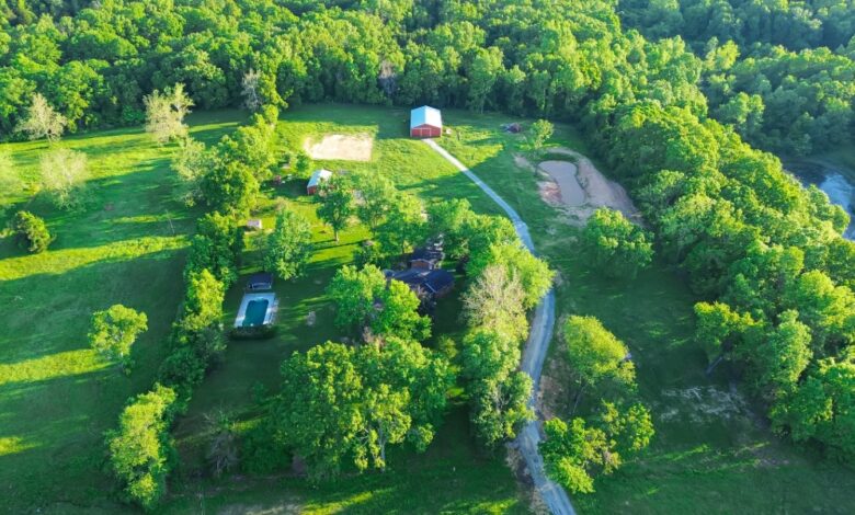 An aerial view shows a long service route linking two farmhouses, a group of storage sheds, and the surrounding acreage.