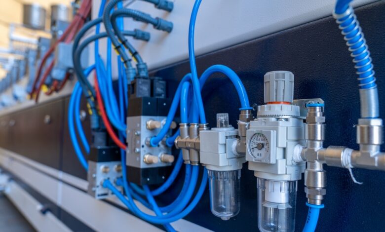 Pneumatic system with blue air hoses, pressure regulator, filters, valves, and metal fittings mounted on machinery.