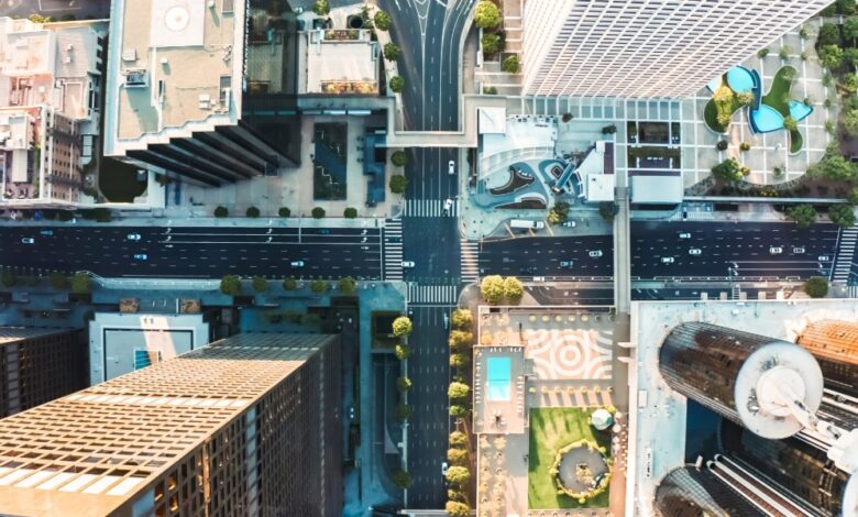 A bird's eye view of a downtown intersection that cuts through high-rise buildings, with small cars on wide streets.