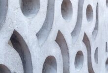 Close-up of a white concrete breeze block wall featuring repeating circular, curved, and geometric openings.