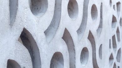 Close-up of a white concrete breeze block wall featuring repeating circular, curved, and geometric openings.