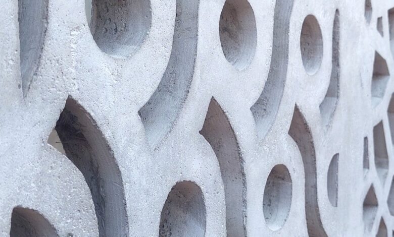 Close-up of a white concrete breeze block wall featuring repeating circular, curved, and geometric openings.