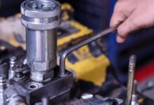 A person is using a tool on a piece of machinery. The machine is made of metal and shows signs of wear.
