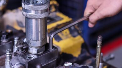 A person is using a tool on a piece of machinery. The machine is made of metal and shows signs of wear.