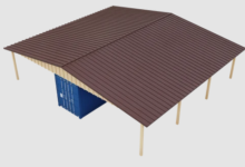 A storage structure with a brown roof, light support posts, cream siding, and a blue shipping container.