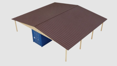 A storage structure with a brown roof, light support posts, cream siding, and a blue shipping container.