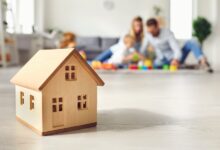 A family is sitting on a floor in the background—they are out of focus. In the foreground is a small house.