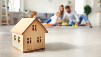 A family is sitting on a floor in the background—they are out of focus. In the foreground is a small house.