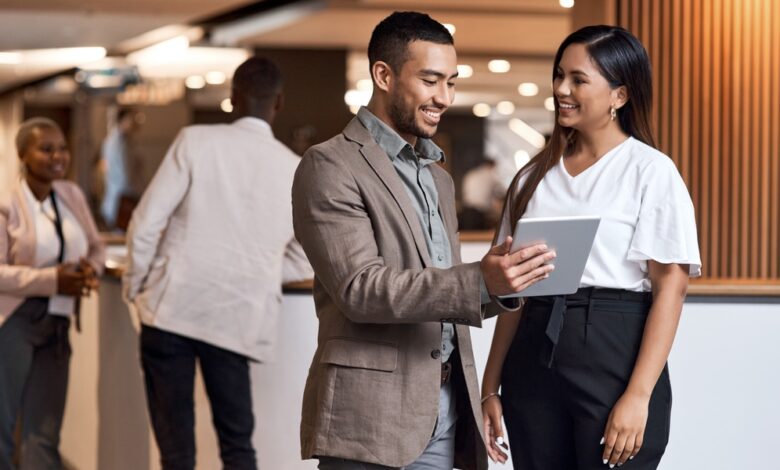 Two professionals talking at a trade show near two other employees. One of them holds a small tablet.